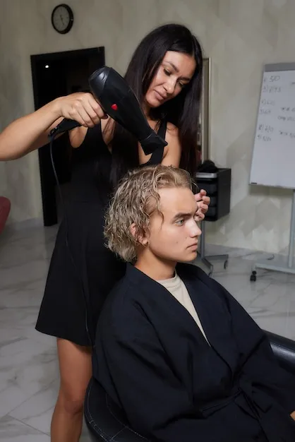 Stylist carefully trimming a woman's hair to create soft layers and a polished finish.