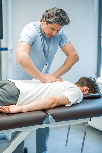 Osteópata manipulando columna vertebral de paciente.