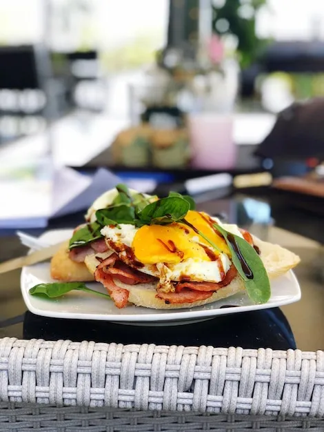 Inviting brunch table setup featuring Eggs Benedict, burrata salad, coffee cups, and warm restaurant ambiance in Miami.