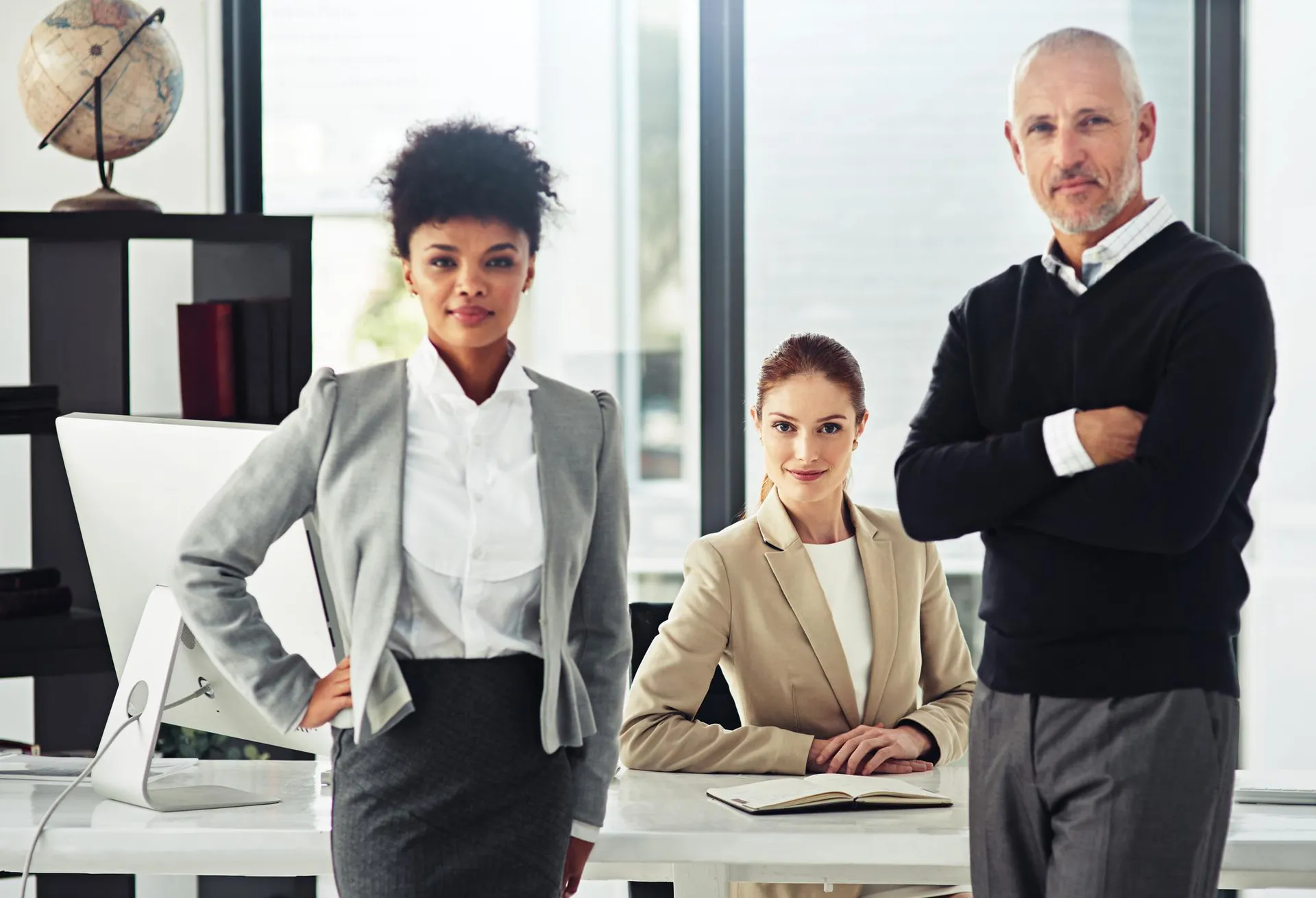 Team of attorneys in business attire posing confidently in a contemporary law office environment.
