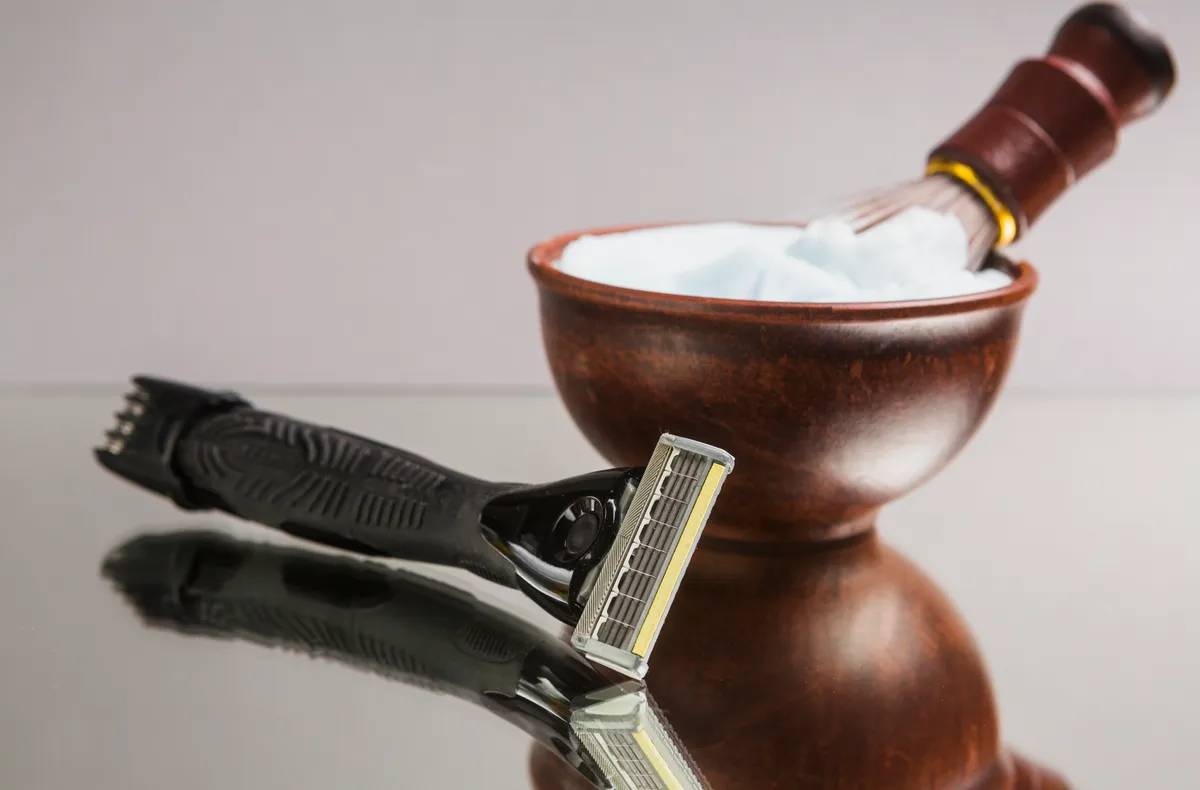 Client enjoying a hot towel straight-razor shave in a barbershop setting.