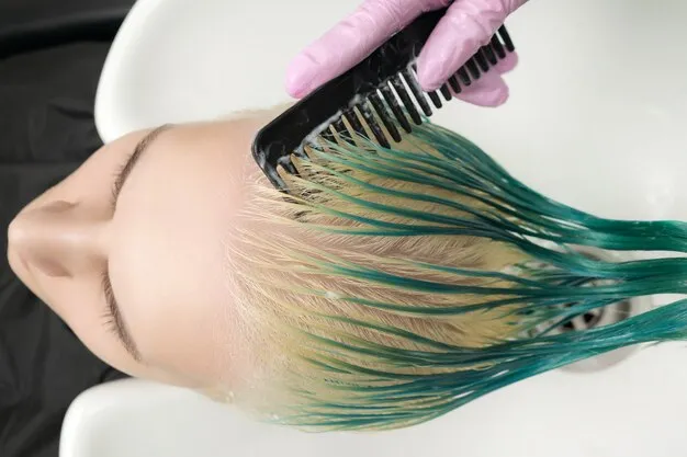 Close-up of stylist applying root touch-up color to client's hair.