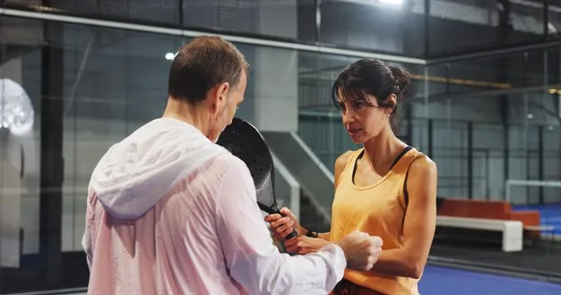 Instructor guiding novice player through padel techniques.