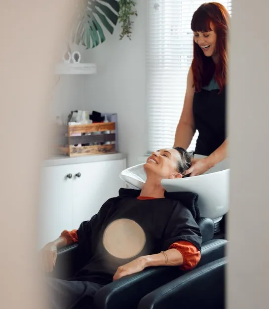 Mujer recostada recibiendo masaje capilar con aceites en ambiente de salón spa.