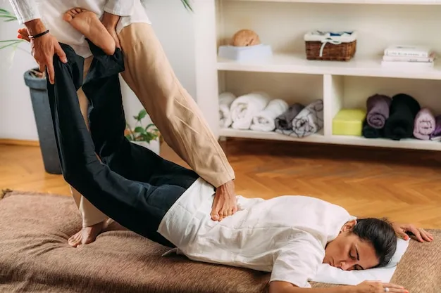 Therapist assisting client in a gentle stretch during Thai massage session.
