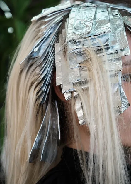 Detailed process of applying highlights with foils on a client's hair.