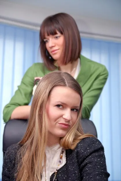 Stylist carefully cutting a woman's long hair into a layered style at a salon station.