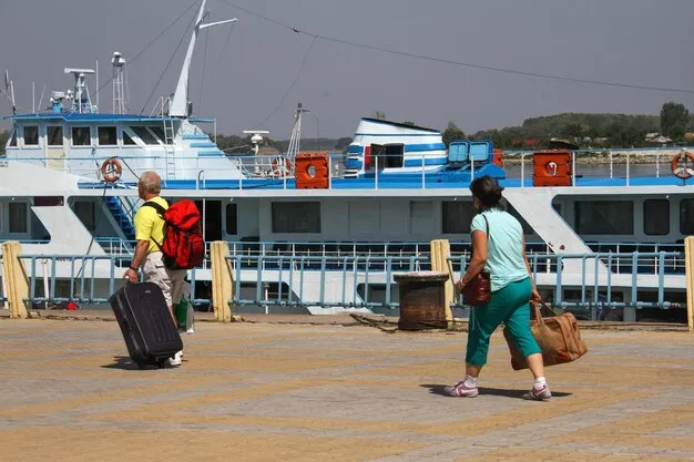 Staff members helping travelers with their luggage carts at the port entrance.