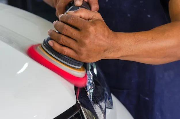 Auto detailer buffing car paint to perfection with polishing tool.