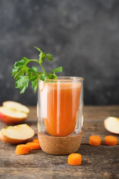 Tall glass of fresh carrot juice garnished with mint.
