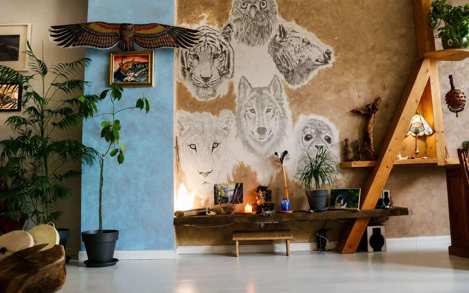 Mural artístico con dibujos de animales (tigre, búho, lobo, león, foca) en una pared de tonos tierra, decorado con plantas y elementos espirituales.