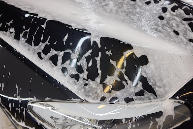 Shampoo premium aplicado en la carrocería de un coche para limpieza profunda.