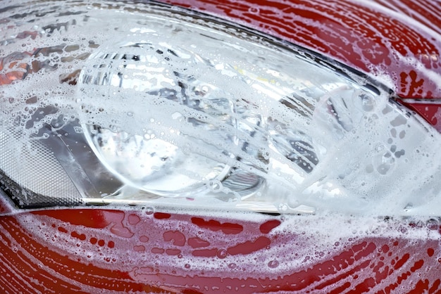 Foamy suds cascading over a polished car body during expert exterior wash.