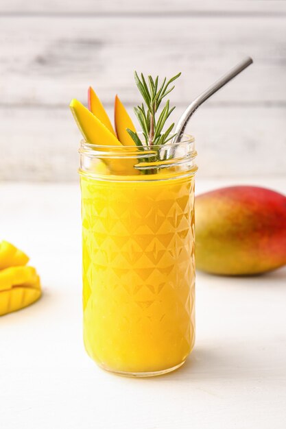 Smooth mango smoothie topped with fresh mango pieces.