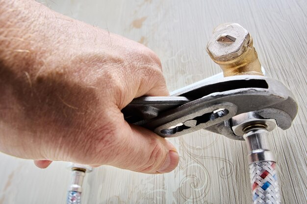 Plumber repairing a water leak under a kitchen sink.