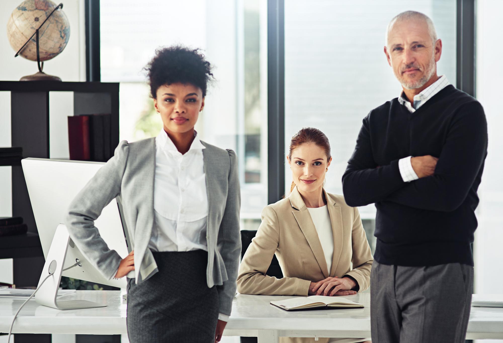 Team of attorneys in business attire posing confidently in a contemporary law office environment.