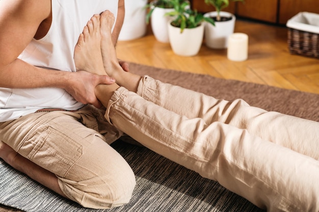 Close-up of therapist's hands performing reflexology on client's bare foot.