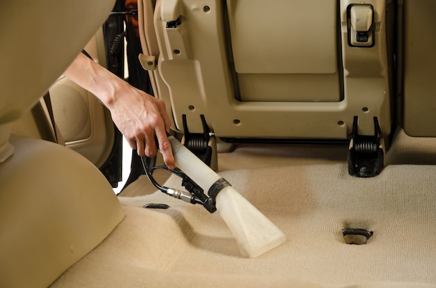 Vacuum cleaner detailing car seats and floor mats.