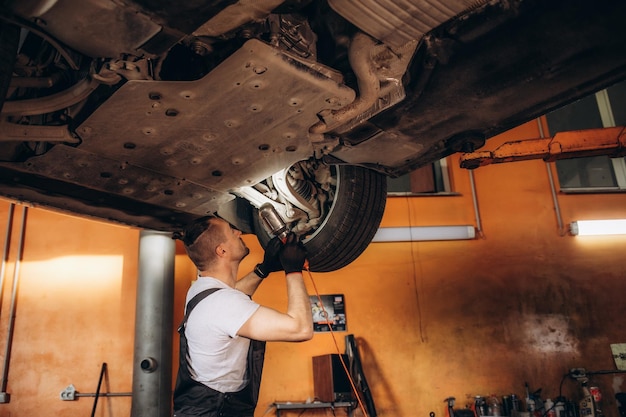 Auto technician working on vehicle suspension system.