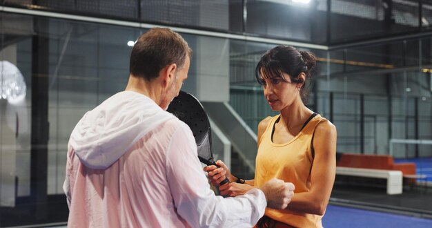 Instructor guiding novice player through padel techniques.