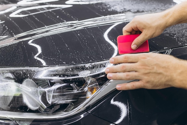 Transparent protection film covering vehicle headlights and trim.