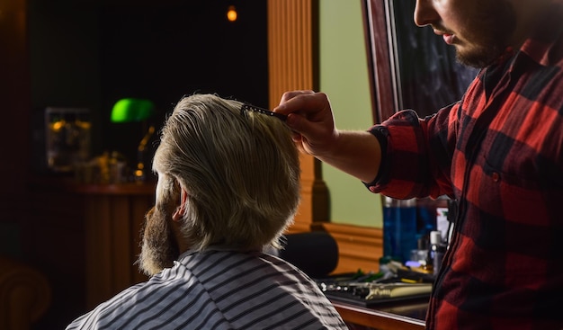 Peluquero cortando cabello corto de un hombre con tijeras.