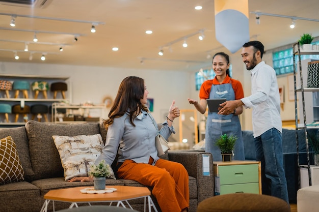Equipo de la tienda interactuando amigablemente con clientes entre muebles modernos en un ambiente acogedor.