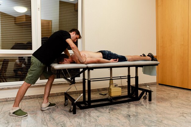 Massage on leg muscles for sports recovery, client in active pose on table.