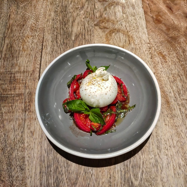 Creamy burrata ball with ripe tomatoes, olive oil, and herbs.
