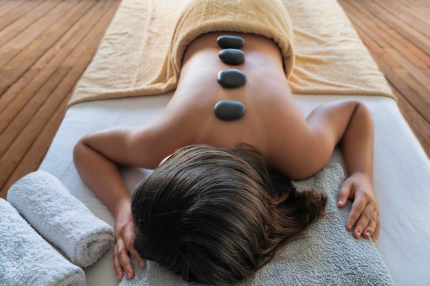 Smooth hot stones aligned along the spine on a client lying face down on a massage table.