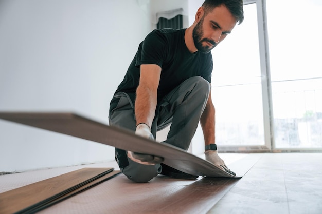 Close-up of technician installing hardwood flooring in apartment.