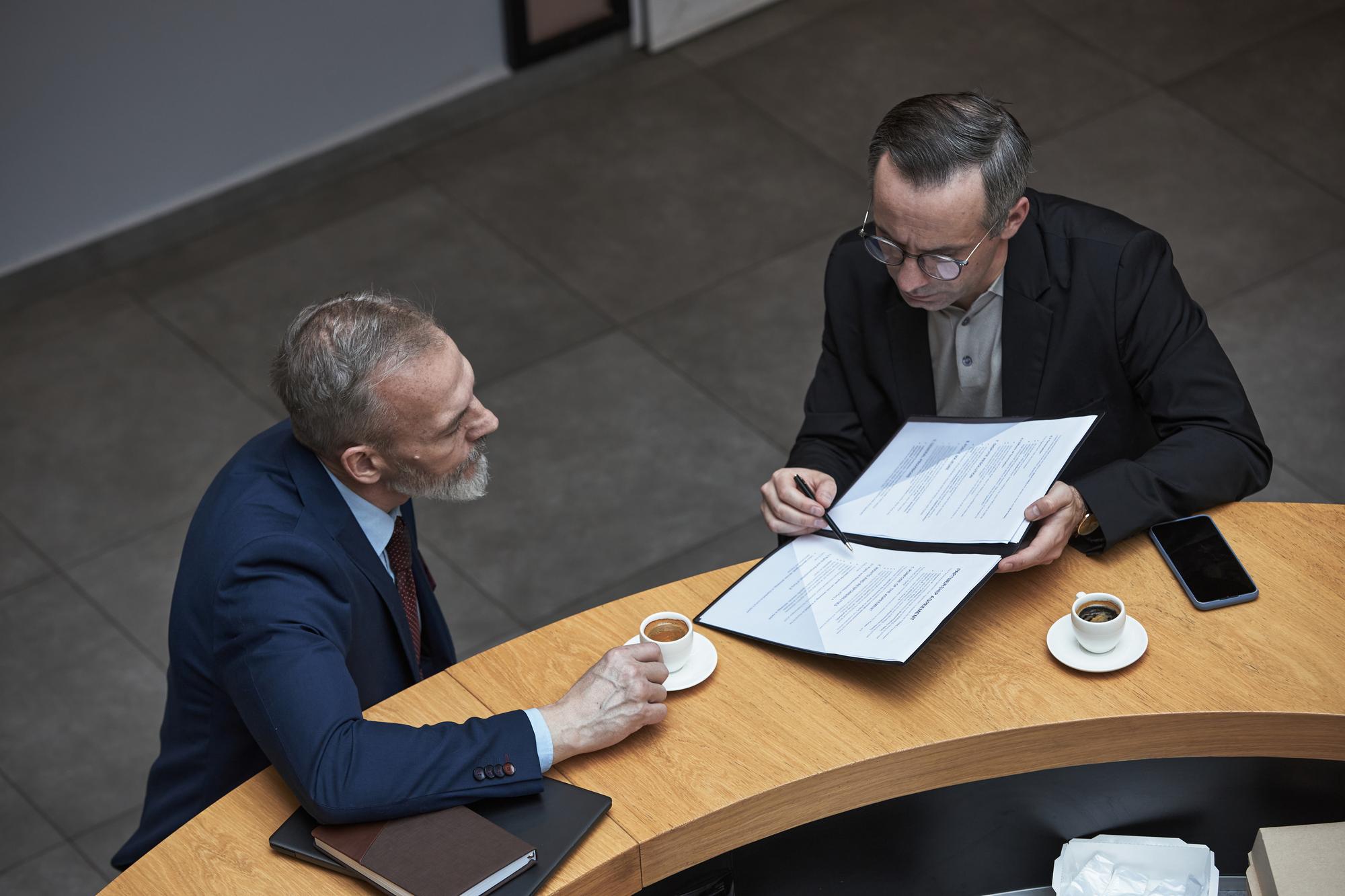 Attorney examining business contracts alongside business owner.