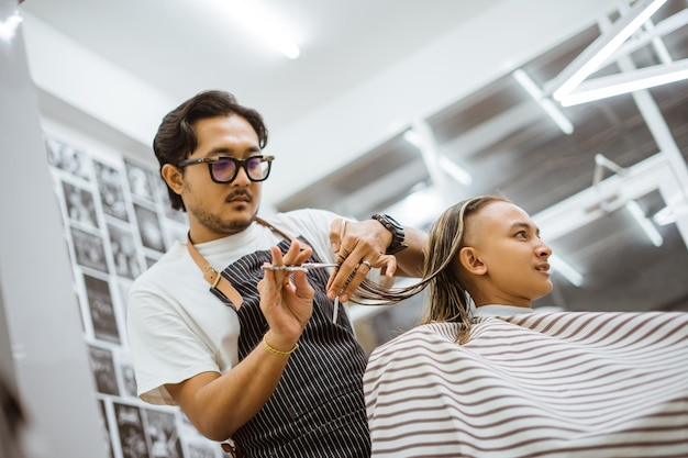 Estilista cortando cabello con precisión en salón de peluquería.