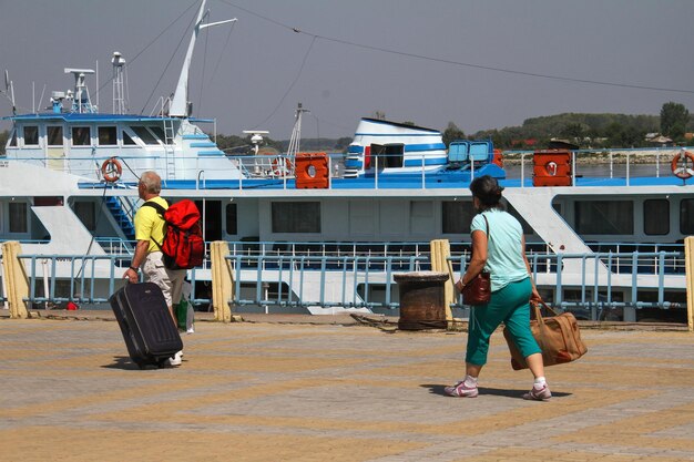 Staff members helping travelers with their luggage carts at the port entrance.