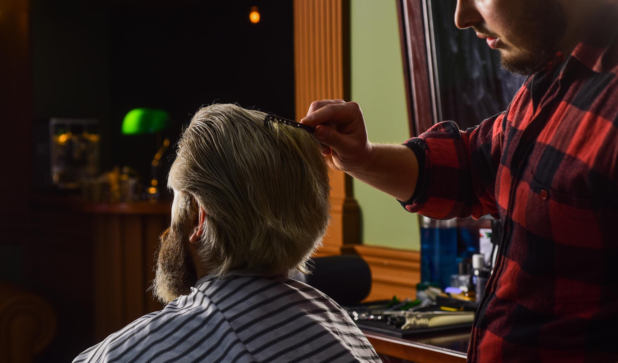 Barber skillfully creating a fade haircut on a client using clippers and scissors.