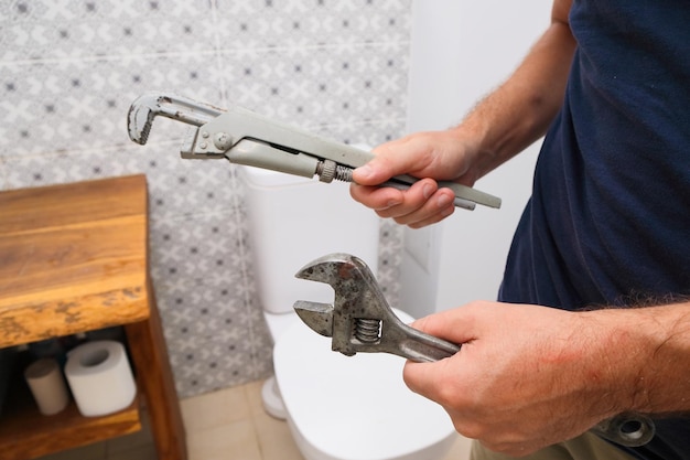 Close-up of plumber tightening fittings on a leaking pipe.