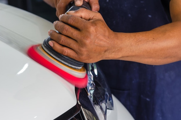 Auto detailer buffing car paint to perfection with polishing tool.