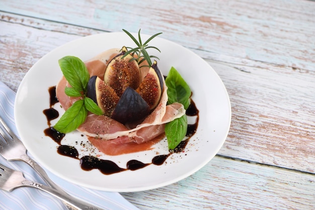Seared foie gras starter garnished with figs and balsamic on a fine china plate.