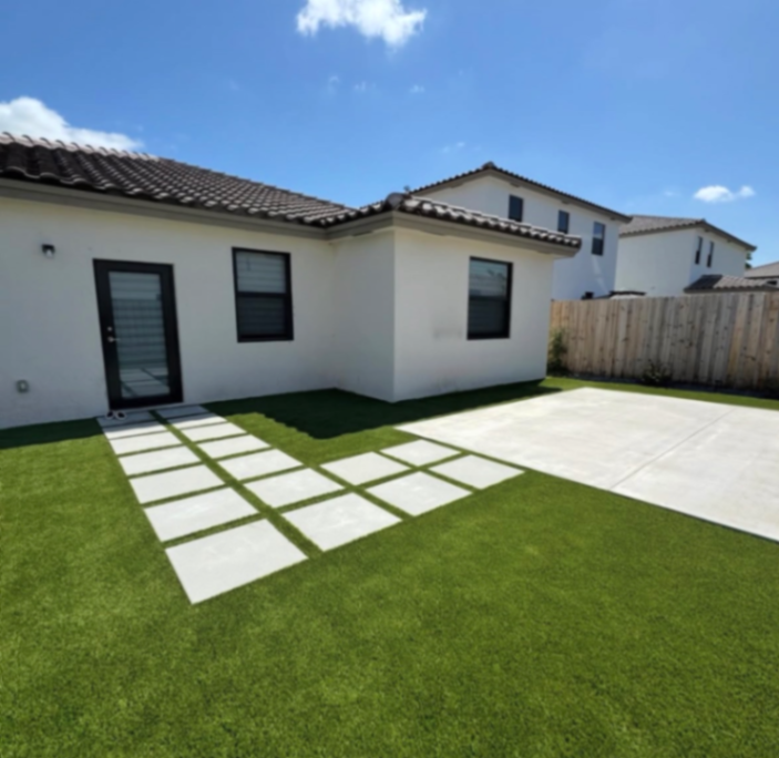 Stunning Miami backyard transformation featuring artificial turf, pavers, concrete, and custom putting green by Aragon Exteriors.
